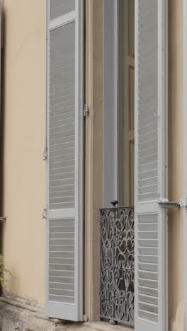 architectural details: open shutters and wrought iron railing on a building facade