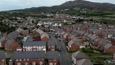 Aerial view descent to Welsh suburban neighbourhood community property rooftops with rocky mountain