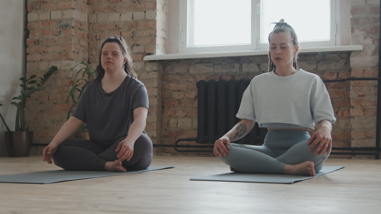 Young Woman With Down Syndrome And Female Trainer Meditating