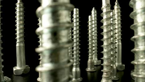 close-up view of metal screws standing upright on a dark background