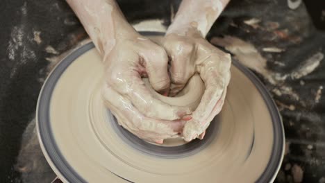 a woman potter makes dishes from clay. a woman makes a jug on a potter's wheel