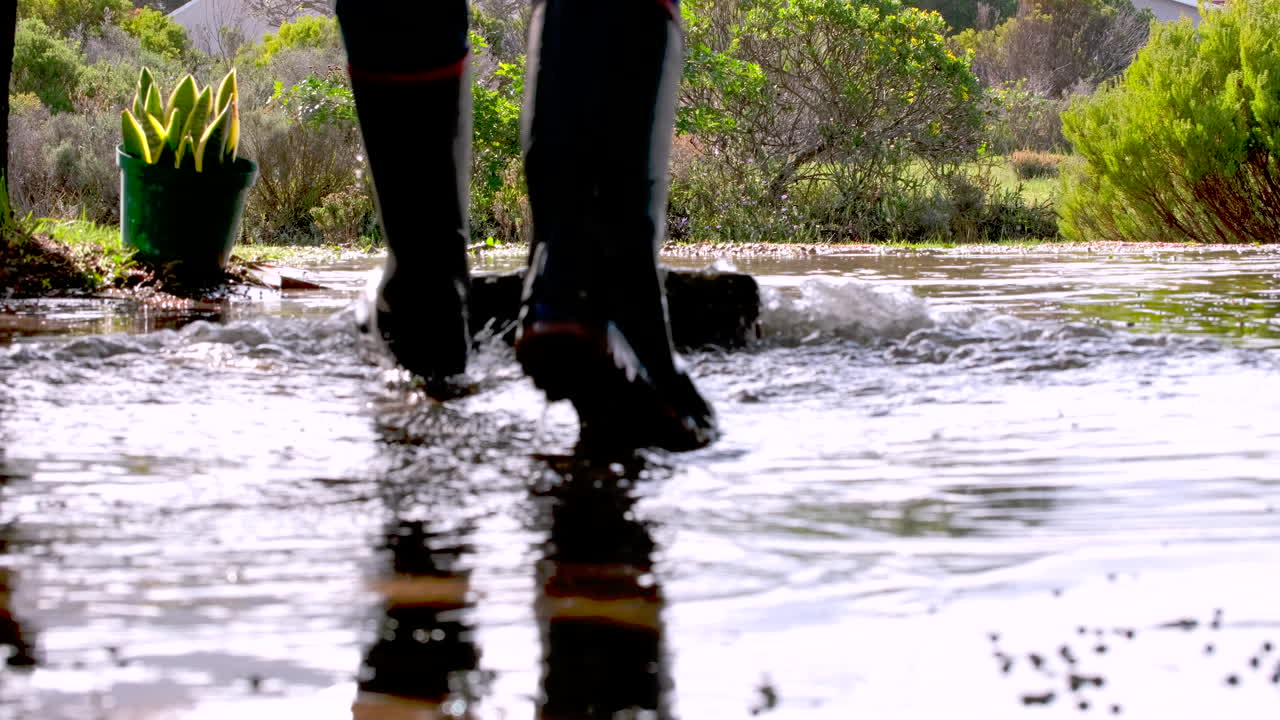 Standing rainwater in driveway being swept away after heavy downpour, low angle