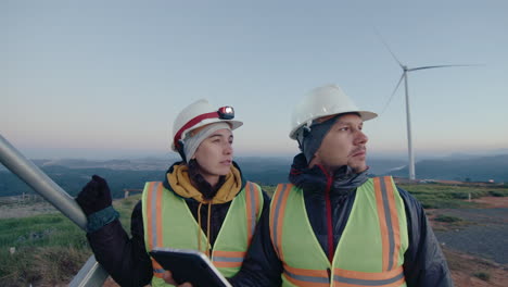 technicians working with tablet and speaking at wind power plant