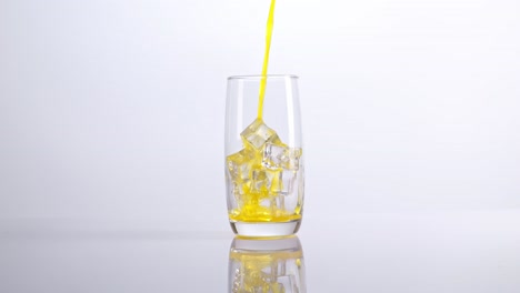 pouring orange juice into a glass with ice