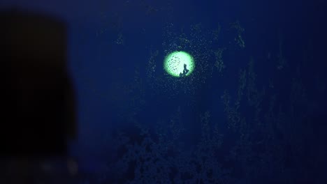 glowing streetlight shines through rain and sleet streaked icy window at night