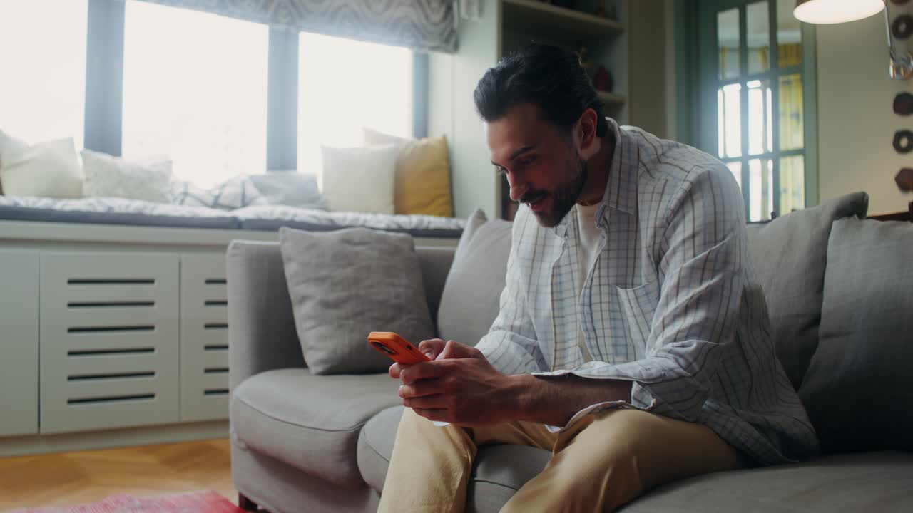 Man using a smartphone on a couch in a modern living room