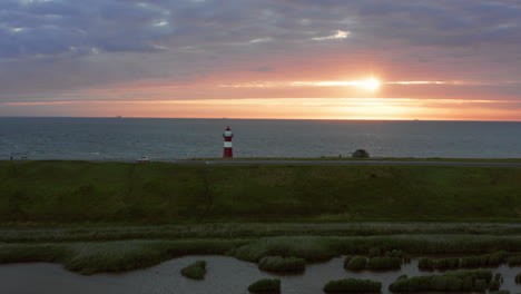 el faro de westkapelle durante una puesta de sol naranja brillante, con mucho viento