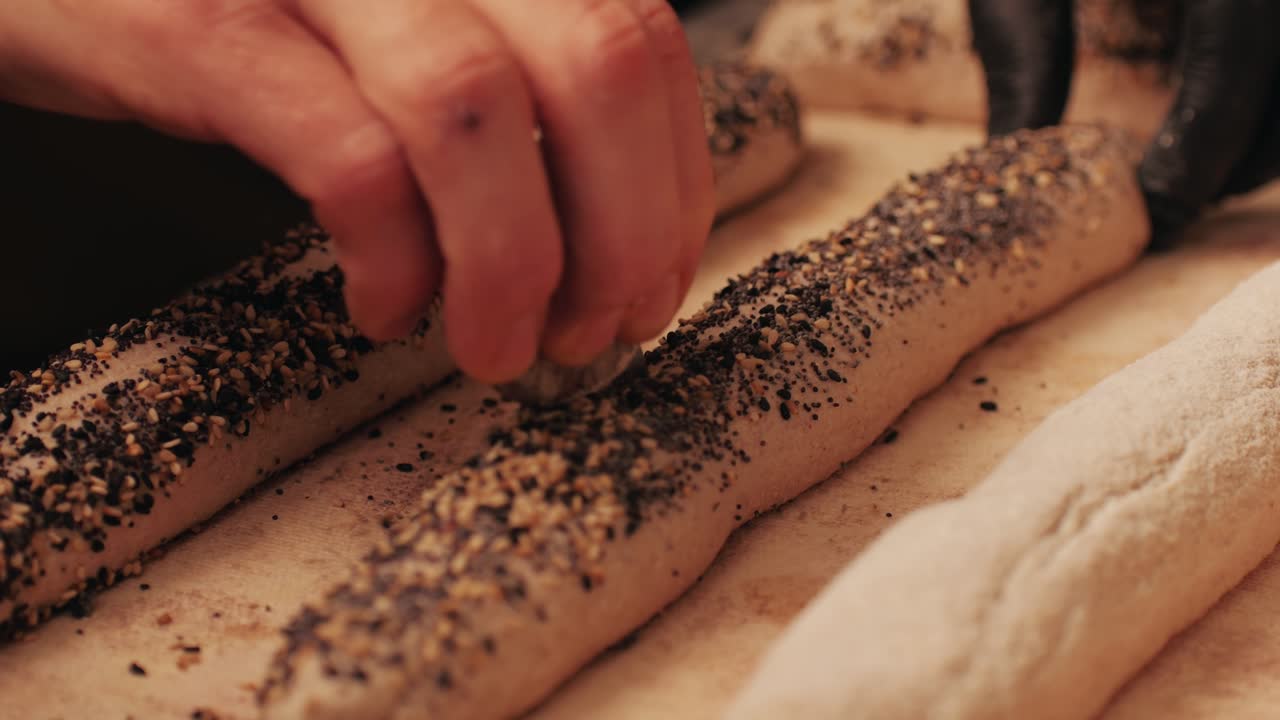 Bakery chef making fresh Artesian buns and baguettes using traditional recipe close-up. Young man kneading dough. Artisan bread is making by skill bakers using natural and high-quality ingredients. Food with health and flavour benefits. Bakery shop and market