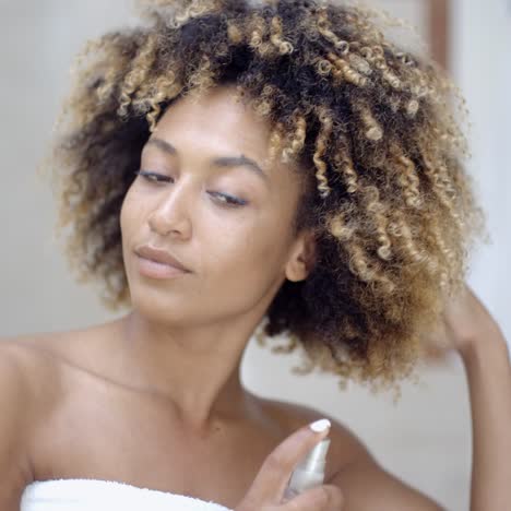 mujer usando spray para el cabello en el baño