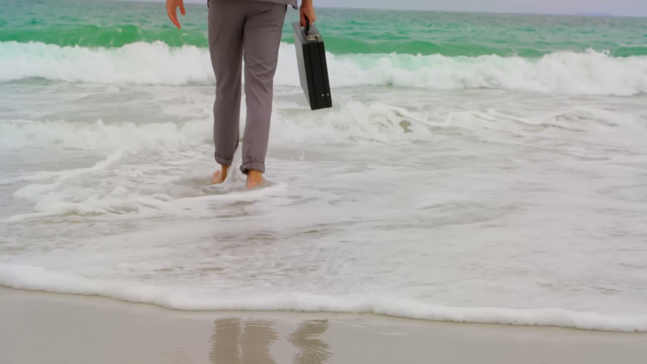 해변 4k에 브리프케이스와 함께 맨발로  ⁇ 는 사업가의 낮은 섹션