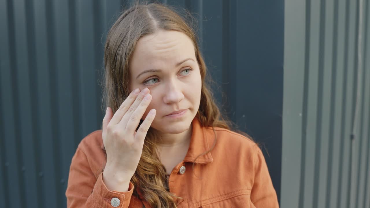 una joven triste se limpia la lágrima de la cara después de llorar