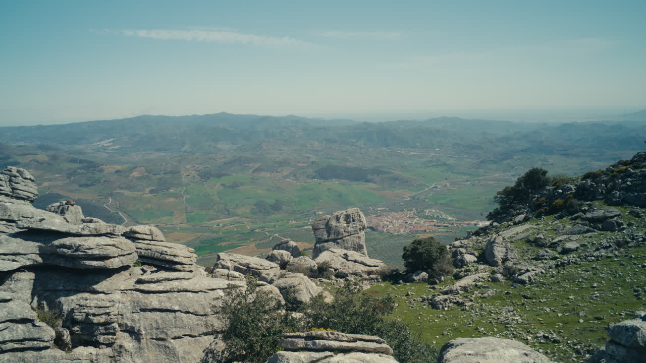Vista panoramica sulla valle e sulla città da El Torcal de Antequera, Spagna, che mostra formazioni carsiche, un vasto paesaggio e uno scenario rurale sotto un cielo sereno.