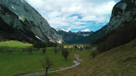 Aerial-flight-at-scenic-Ahornboden-Engtal-valley-toward-the-snowy-glacier-mountain-tops-in-the-Bavarian-Austrian-alps-on-a-cloudy-and-sunny-day-along-trees,-rocks,-forest-and-hills-in-nature