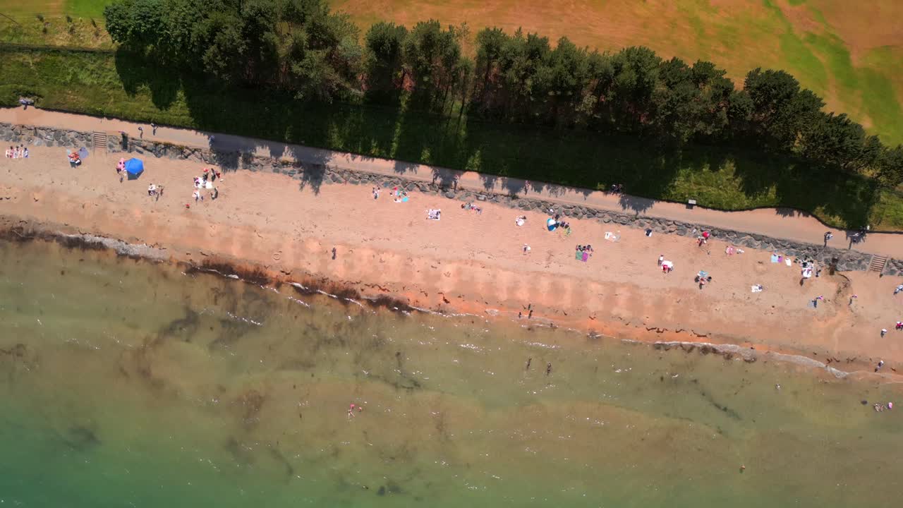 Rotating overhead aerial video of Helen's Bay beach in County Down, Northern Ireland, UK on a bright summer day. Filmed in 4K, 60FPS and with Rec709 color
