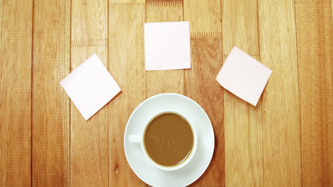primer plano de una taza de café con un platillo y una nota adhesiva