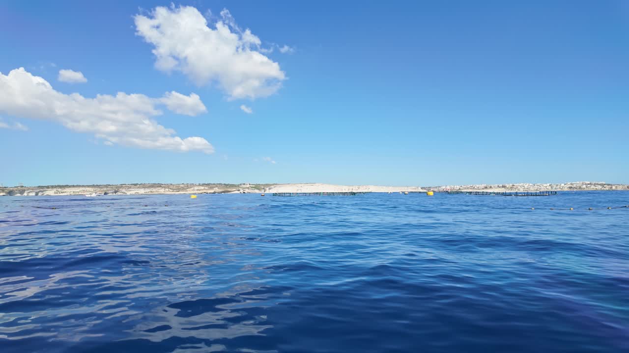 Indicator buoys and nets of a tuna farm in the Mediterranean Sea with the Marsaskala coastline in the background in Malta.