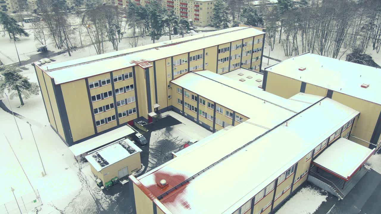 Aerial drone footage of a highschool in Tallinn Estonia Called TTG or Tallinna Tehnika gümnaasium during winter cold day with white snow. The school is surrounded by apartment buildings, Lepistiku