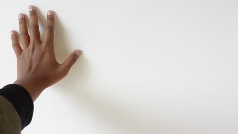 a mão de uma pessoa a tocar uma parede branca.