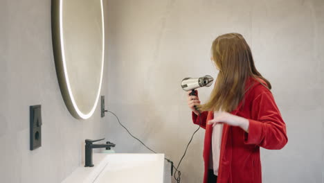 mujer secando el cabello en el baño