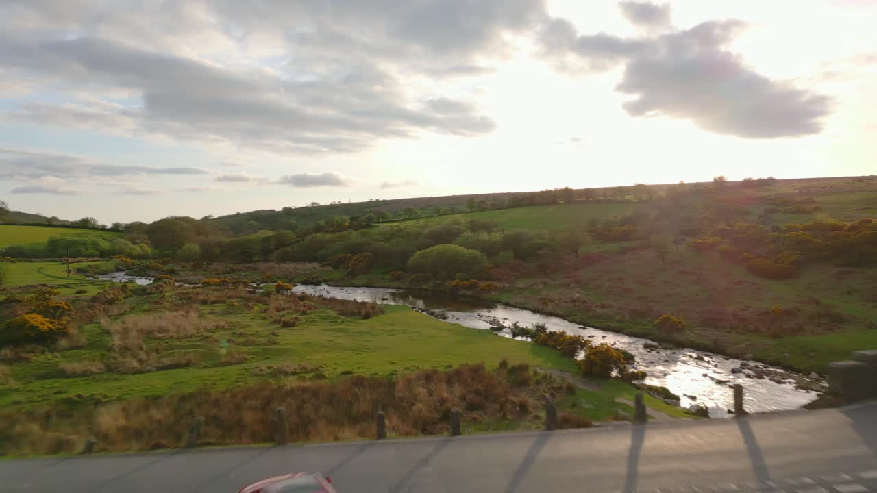 ⁇ 은 차 가 잉글랜드 의 다트무어 에 해 가 지는 동안 중세 의 돌 다리 와 교차점 에 도착 하고 있다