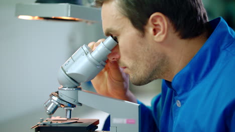 investigador masculino que trabaja con el microscopio. microscopio médico de investigación