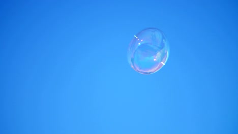 close-up. a big soap bubble flies against the blue sky