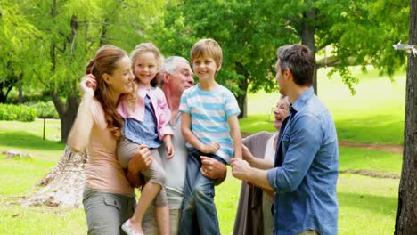 familia de varias generaciones posando y riendo a la cámara en un parque
