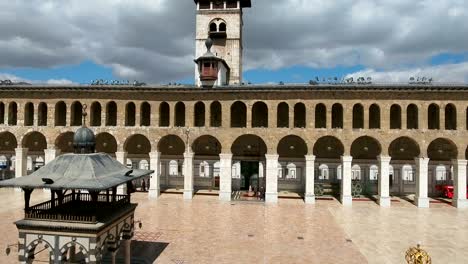 view from the center of the umayyad mosque, going to a view of the city of damascus in syria. drone is flying in the inner courtyard of the mosque, where we see the building exterior inside the mosque.