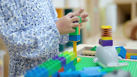 little girl playing with colorful lego blocks at indoor playroom