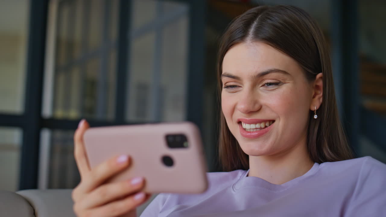 Calm lady holding mobile phone in apartment room closeup. Girl browsing online