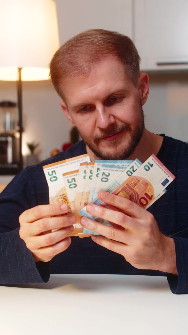 Man räknar eurosedlar, planerar drömköp, nöjd med lön, besparingar, bonus och investeringar på natten