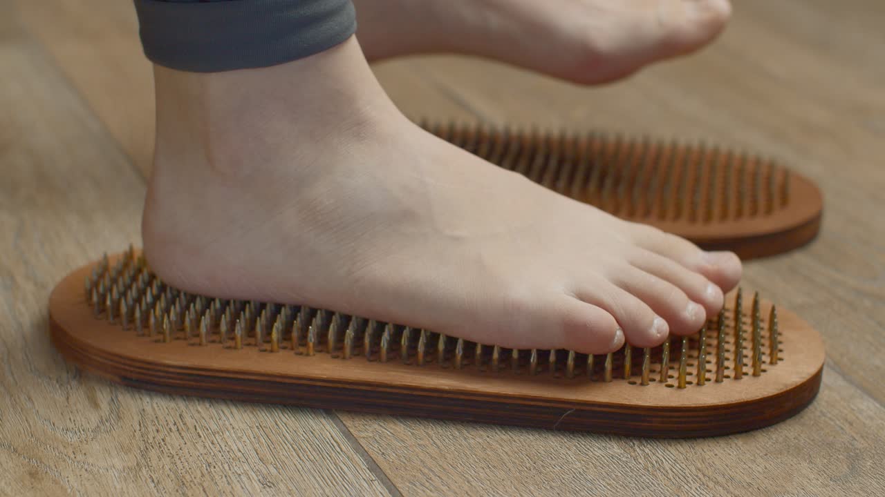 Piedi di bambino su un tappetino da riflessologia in legno