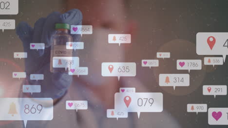 holding covid-19 vial, healthcare worker with animation of social media notifications