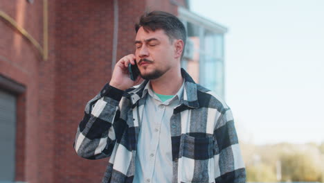 mature caucasian man having conversation communicate speaking by smartphone in downtown city street