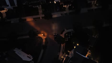 aerial tracking shot of car on street in dark neighborhood