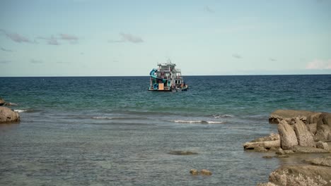 a floating party boat is anchored off sairee beach in koh tao, thailand, on a calm morning, showcasing a serene coastal landscape and inviting waters.