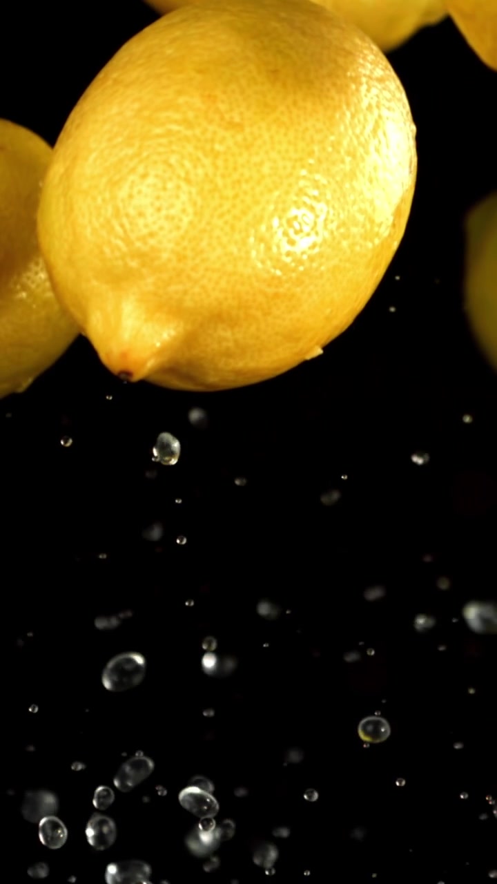 Limoni freschi e goccioline d'acqua al rallentatore su sfondo nero