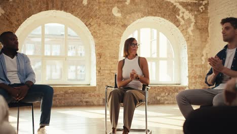 Participants-in-group-therapy-sit-in-a-circle,-chat-and-applaud-each-other.-The-camera-rotates-in-a-circle,-an-overview-of-the