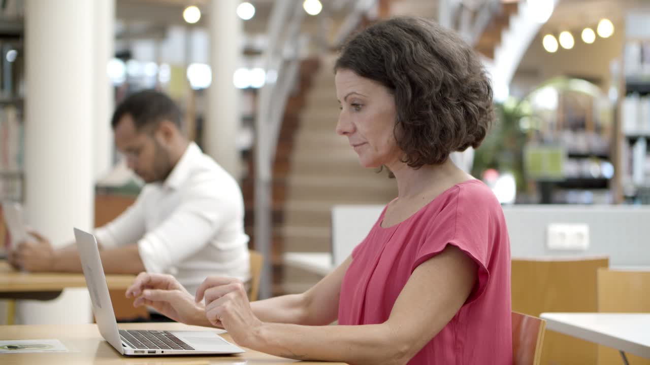vista lateral de una mujer caucásica pensativa usando una laptop
