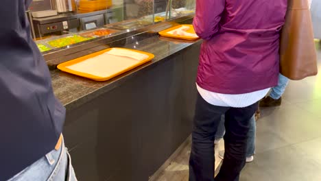 personas haciendo cola para recoger su almuerzo en un restaurante