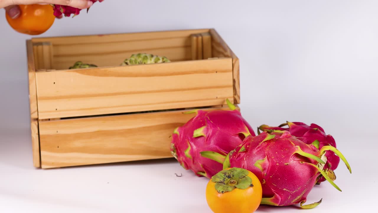 manos colocando frutas en una caja de madera