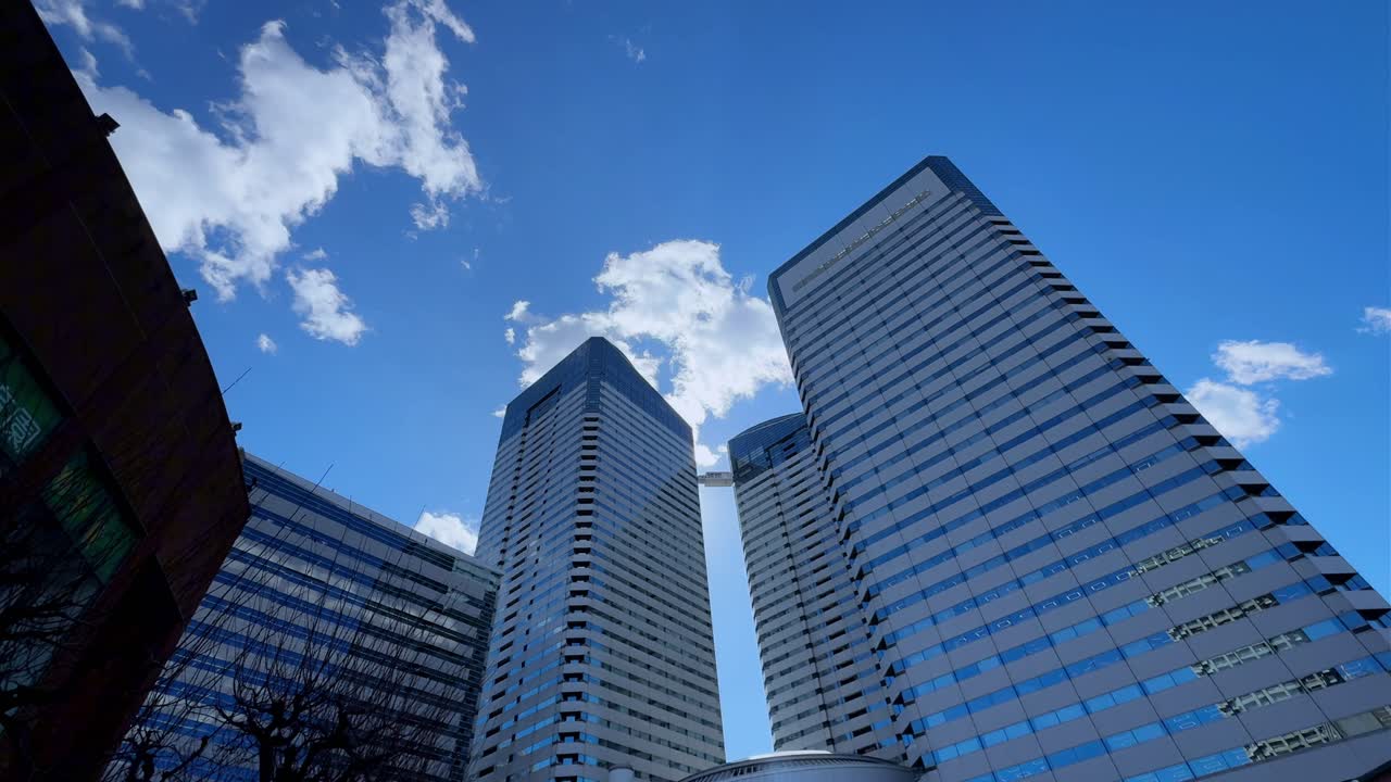 Modern skyscrapers in Harumi, Tokyo, under a bright blue sky with scattered clouds