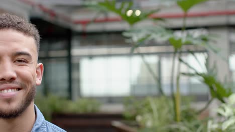 retrato de mitad de cara de un hombre biracial sonriendo en el balcón de la oficina, espacio de copia