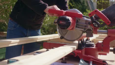 the man is sawing the piece of wood with the circular saw