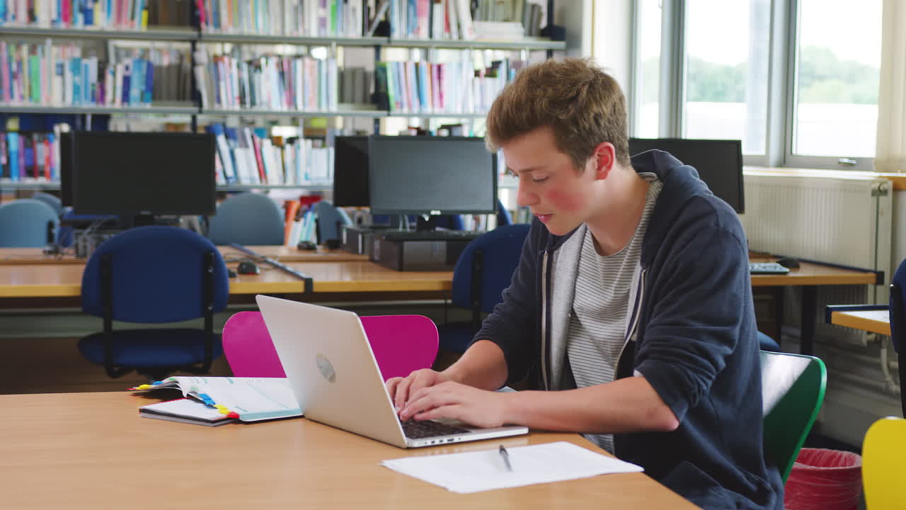 estudiante masculino trabajando en la computadora en la biblioteca de la universidad