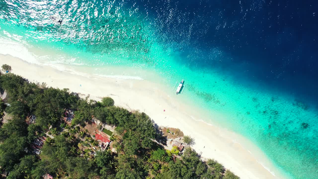 Sabbia bianca di una spiaggia esotica bagnata da una laguna blu turchese con acqua cristallina, barca ancorata sulla riva di un'isola tropicale, Thailandia.