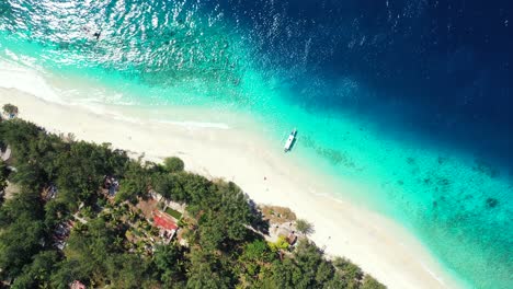 White-sand-of-exotic-beach-washed-by-blue-turquoise-lagoon-with-crystal-water,-anchored-boat-on-shore-of-tropical-island,-Thailand