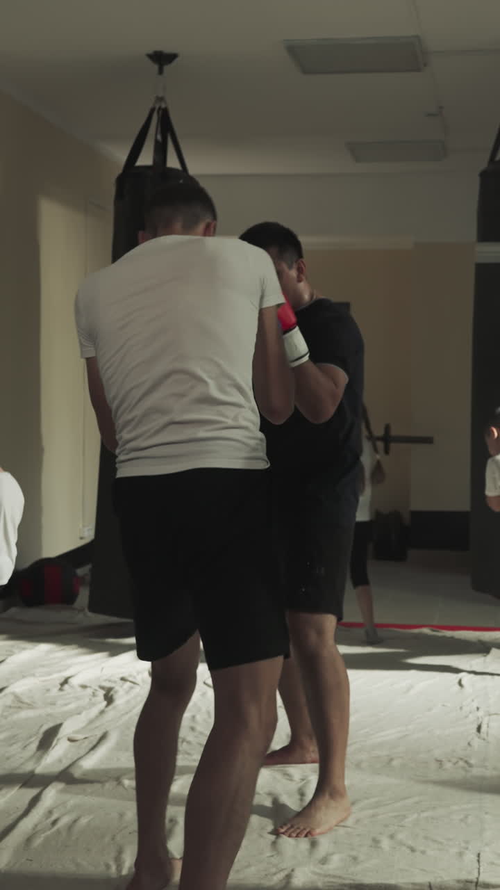 niños y adultos se ejercitan en el club de artes marciales. los kickboxers hacen ejercicios de combate con equipos de golpeo en el gimnasio de lucha en cámara lenta. técnicas de batalla