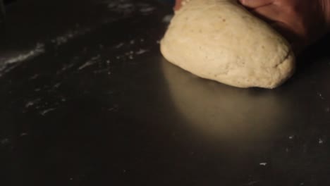 close hands of a female chef deflating pizza dough