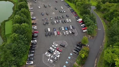 Row-Of-Vehicles-Parked-In-The-Parking-Lot-Surrounded-By-Green-Trees